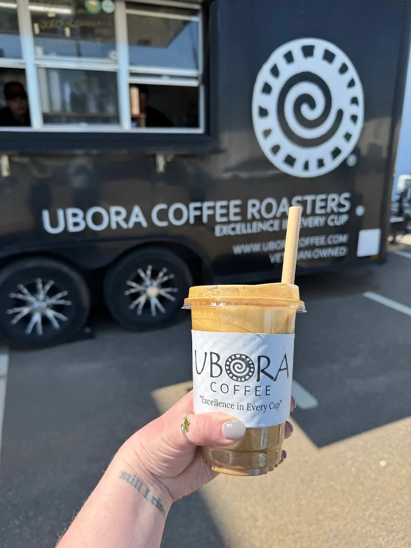 hand holding iced coffee beverage in front of ubora coffee roasters mobile truck., ubora coffee roasters augusta, augusta