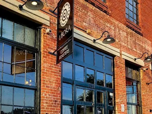 red brick building with coffee shop signage and large blue-framed windows., ubora coffee roasters augusta, augusta
