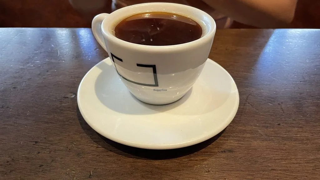 white ceramic cup and saucer filled with black coffee on wooden table., urbe cafe bar, são paulo