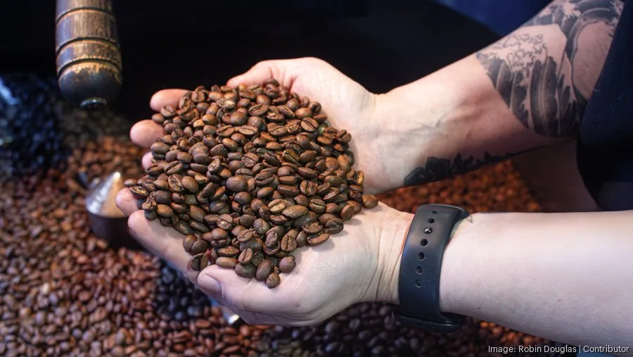 person holding roasted coffee beans with tattoo visible, grinder in background., valiant coffee, auburn