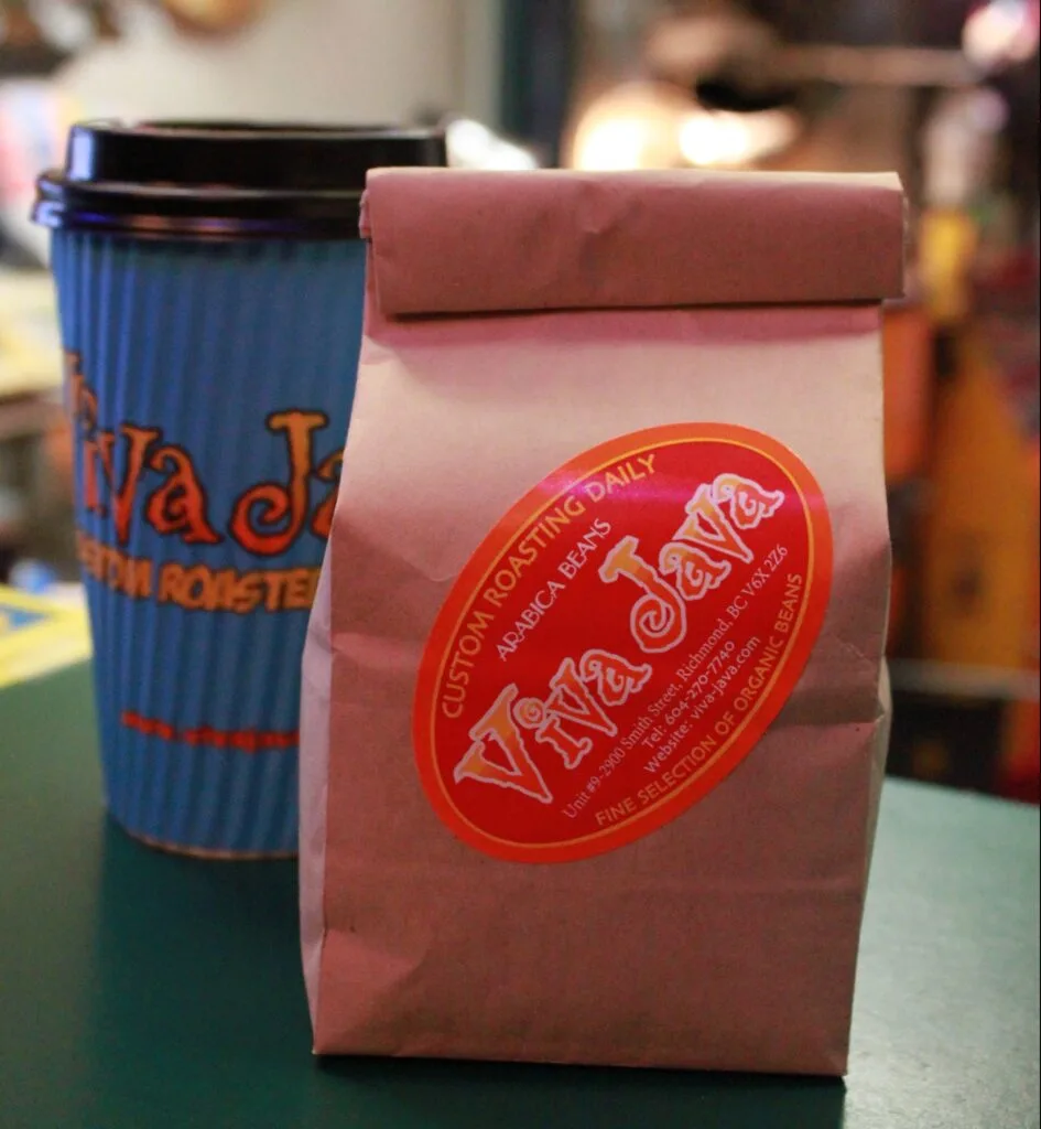 coffee bags displayed on table, one pink viva java brand, one blue cup nearby., viva java., richmond
