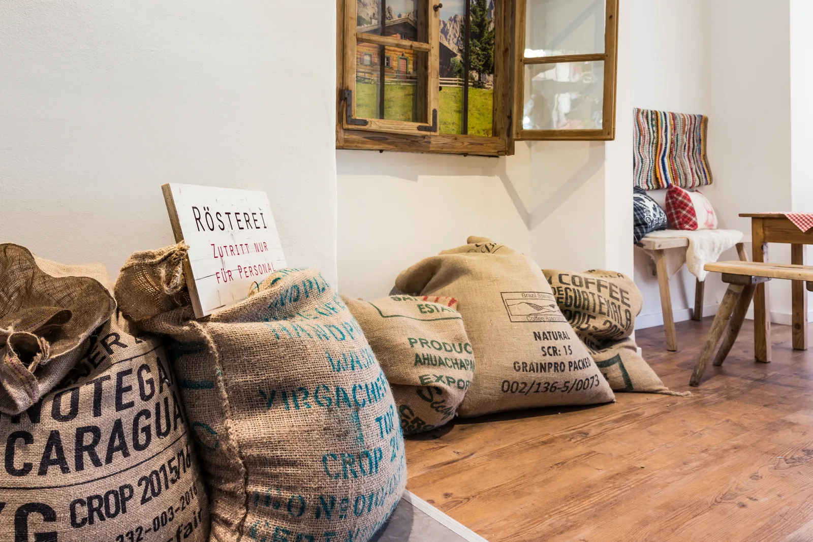 coffee sacks displayed on wooden floor in rustic gallery space with signage., vogelmaier kaffeerösterei, munich