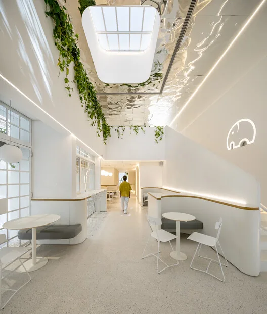modern minimalist corridor with skylights, hanging plants, and contemporary seating areas., we coffee ibirapuera, são paulo