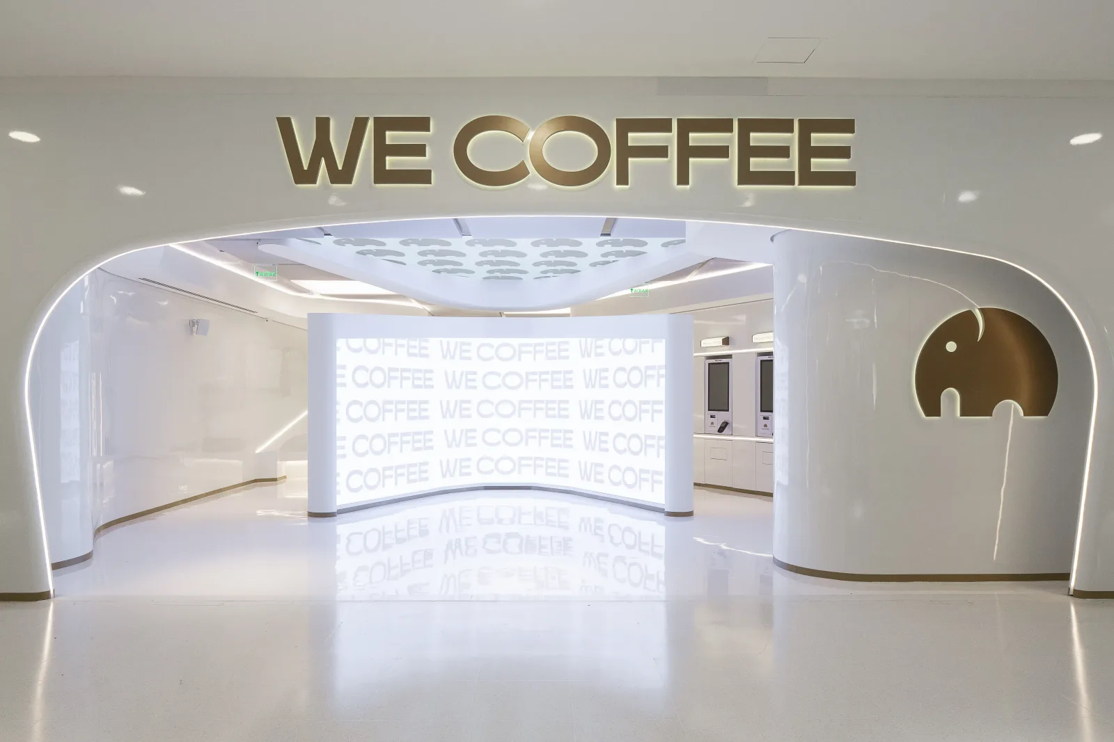 modern minimalist coffee shop interior with illuminated signage and sleek white design., we coffee morumbishopping, são paulo