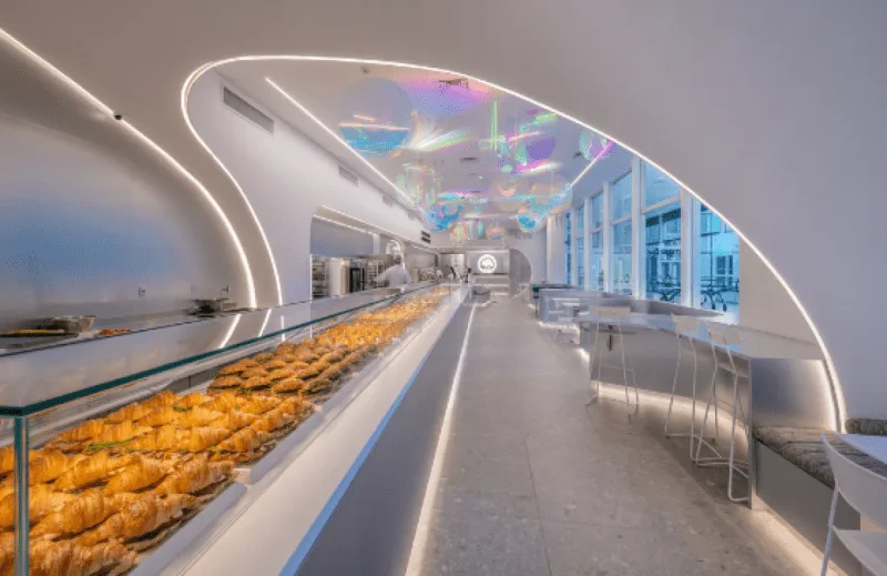 modern bakery interior with golden pastries displayed along curved counter and windows., we coffee tamboré, barueri