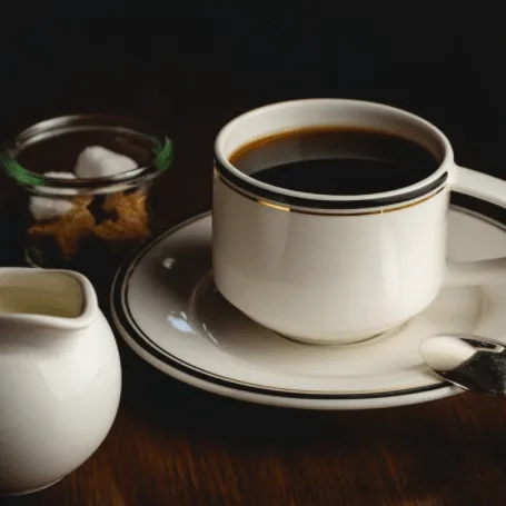 white ceramic coffee cup filled with black coffee on saucer, cream pitcher, and sugar bowl., weathered hands coffee, austin