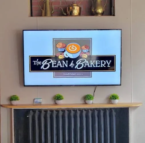 display screen showing the bean & bakery logo above wooden shelf with potted plants., white mountain gourmet coffee, concord