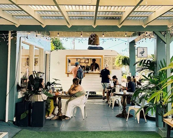 covered outdoor café seating with customers, counter service, and potted plants., white nene coffee, honolulu