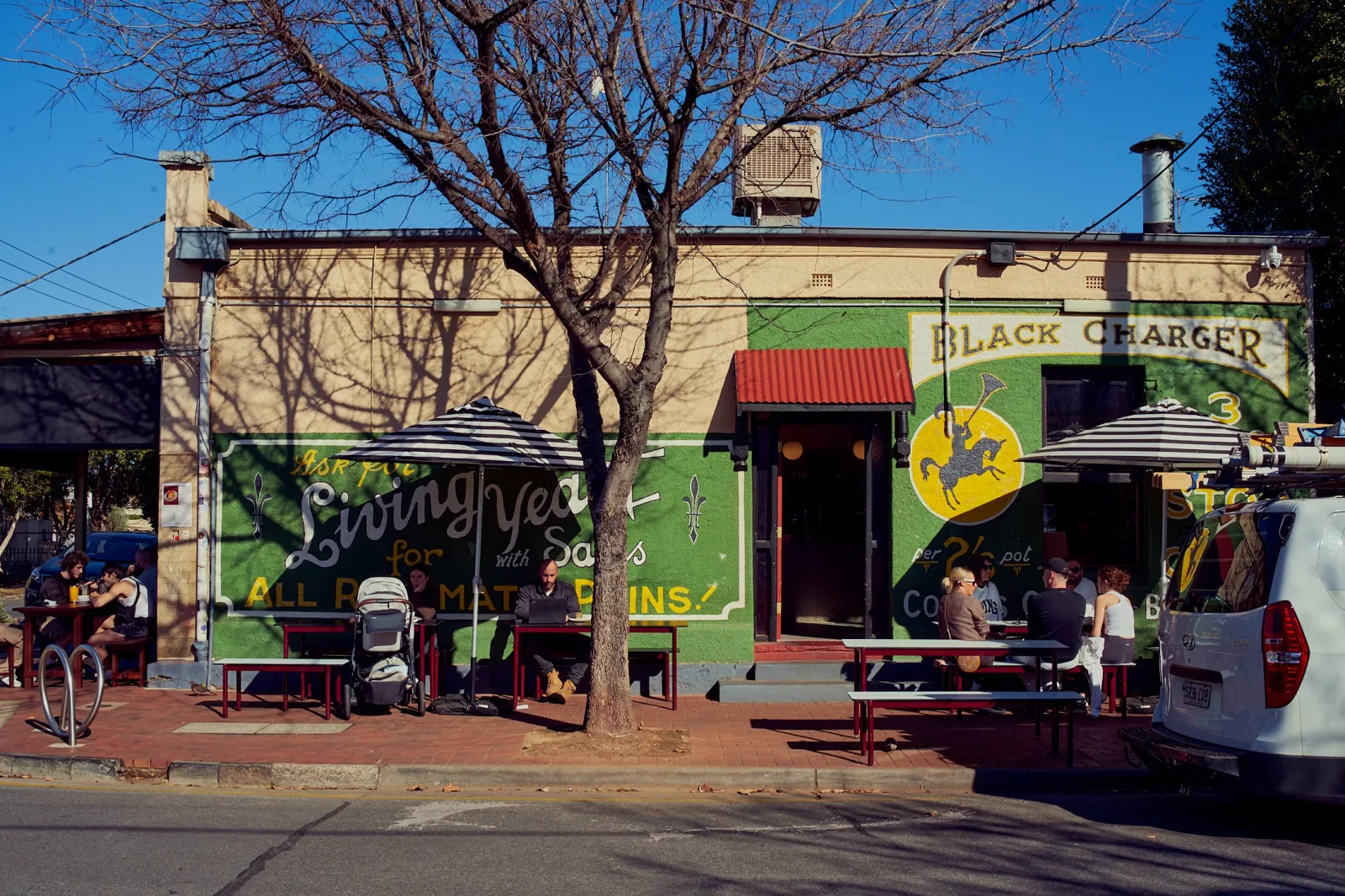 colorful street-front bar with green murals and outdoor seating under bare tree., willow bend coffee roasters, croydon