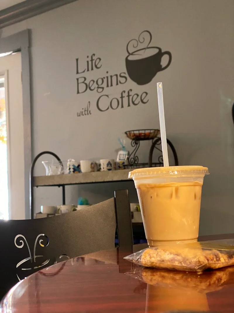 iced coffee beverage on table beneath "life begins with coffee" wall decal., york coffee roastery, south carolina