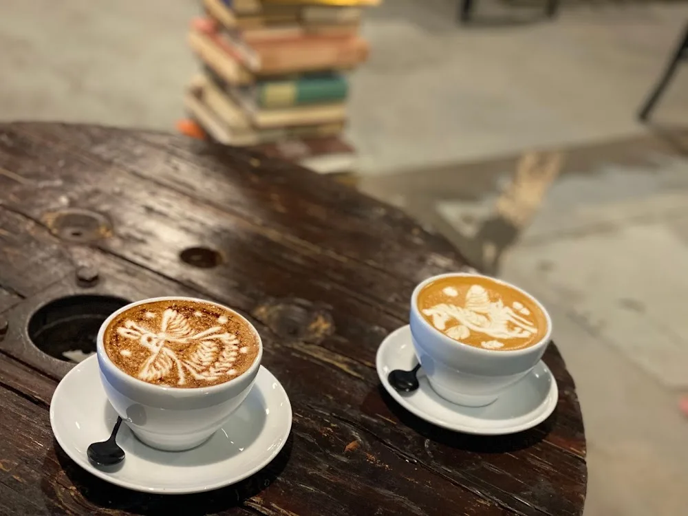 two cappuccinos with decorative latte art on rustic wooden table., zimmah coffee, hobart